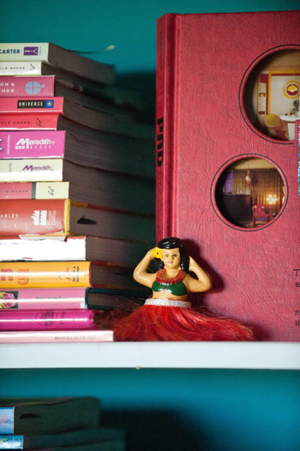 A hula girl perched on a shelf in a home office.