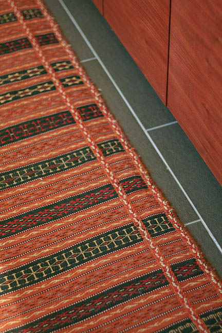 A rust colored Afghanistani runner rug used in a modern master bathroom in Austin, TX.