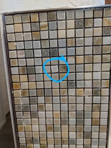 Modern slate tile mosaic backsplash with one misaligned tile