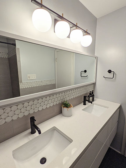 Floating white lacquer double vanity in modern gray bathroom remodel in Austin featuring large white penny accent tile, quartz countertops, and black plumbing fixtures.