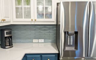 White and blue kitchen remodel featuring glass door cabinets, stainless refrigerator, mid-century modern tile backsplash, white marble quartz countertops