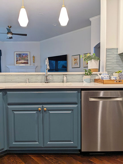 Open concept kitchen remodel blue cabinets white marble quartz countertop sleek stainless dishwasher mid-century pendant lights