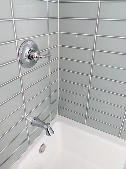 Spa bathroom featuring Arizona Tile Vetri in Acqua and chrome showerhead and tub spout.