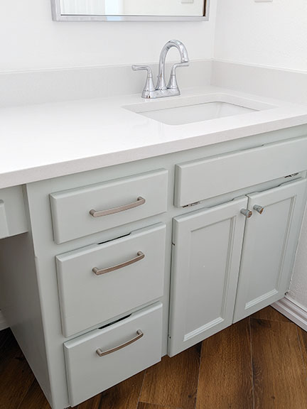 Spa bathroom featuring white quartz countertops, pale mint green vanity cabinet, and chrome fixtures..