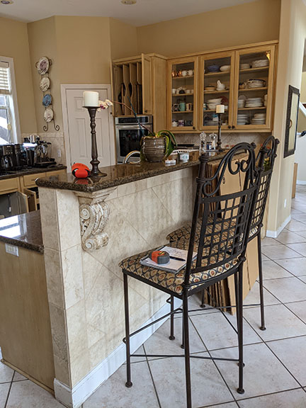 Tuscan kitchen before remodel featuring outdated granite countertops and travertine backsplash, with elevated bar