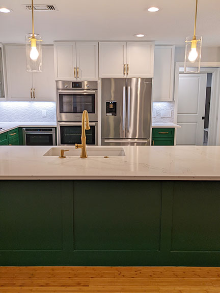 Austin kitchen after remodel, with SW 6454 Shamrock emerald green and white Shaker style cabinetry, brass fixtures, and open concept.