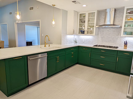 Austin kitchen after remodel, with emerald green and white Shaker style cabinetry, brass fixtures, and open concept.
