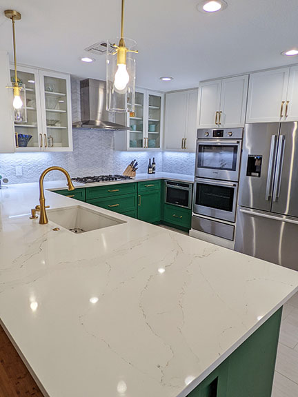 Austin kitchen after remodel, with SW 6454 Shamrock emerald green and white Shaker style cabinetry, brass fixtures, and marble-look quartz countertops.