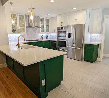 Austin kitchen after remodel, with emerald green and white Shaker style cabinetry and brass fixtures.