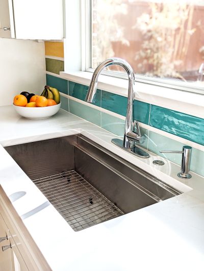 Chrome faucet fixtures and a modern stainless sink with colorful backsplash in Room Fu designed kitchen remodel.