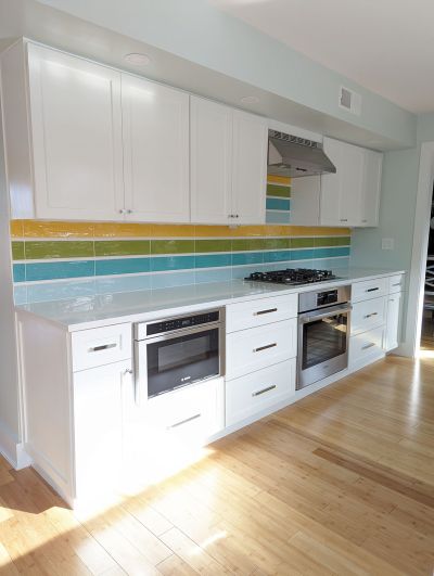 Galley kitchen remodel designed by Room Fu (Austin), featuring colorful backsplash and white cabinetry.